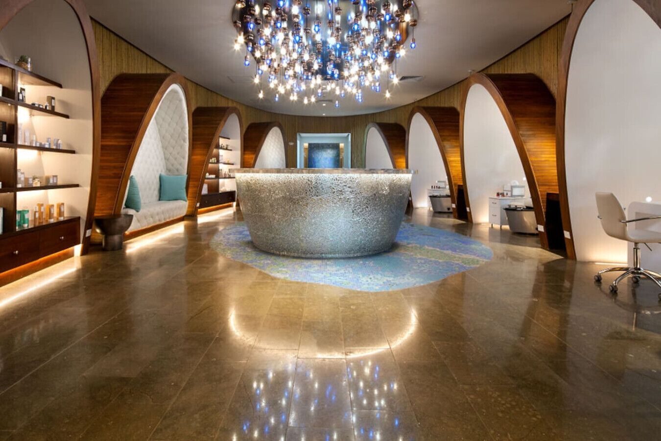 A modern reception area with a central seating area, wooden accents, and a chandelier.