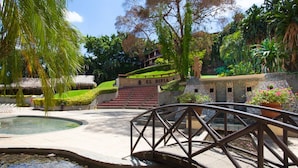 A bridge over a water feature, surrounded by lush greenery and a stone structure with steps leading up to a building labeled "L. DIRIA". - La Diria #303 Best Location, Walk to Beach/Shops! (Tamarindo)