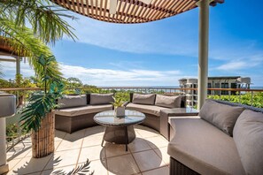 A rooftop patio with wicker furniture, a glass table, and a view of the ocean. - Monte Perla 3 Ocean View near Beach! (Tamarindo)