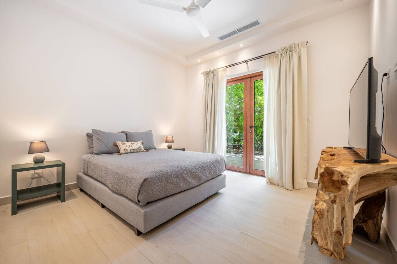 A bedroom with a bed, nightstands, a television, and a wooden table.