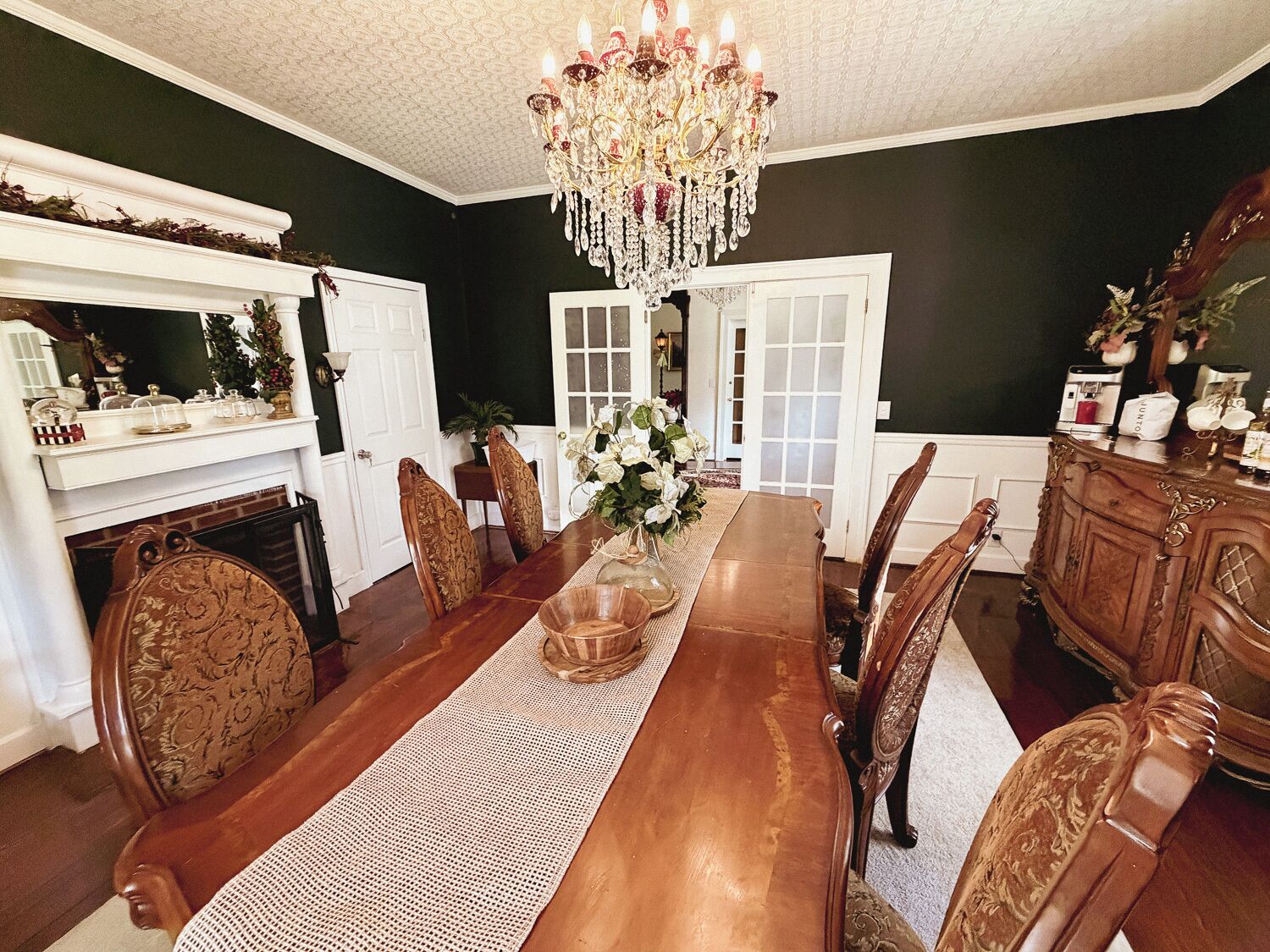 Ein Esszimmer mit Holztisch, Stühlen, einer Chandelier und einem Kamin.