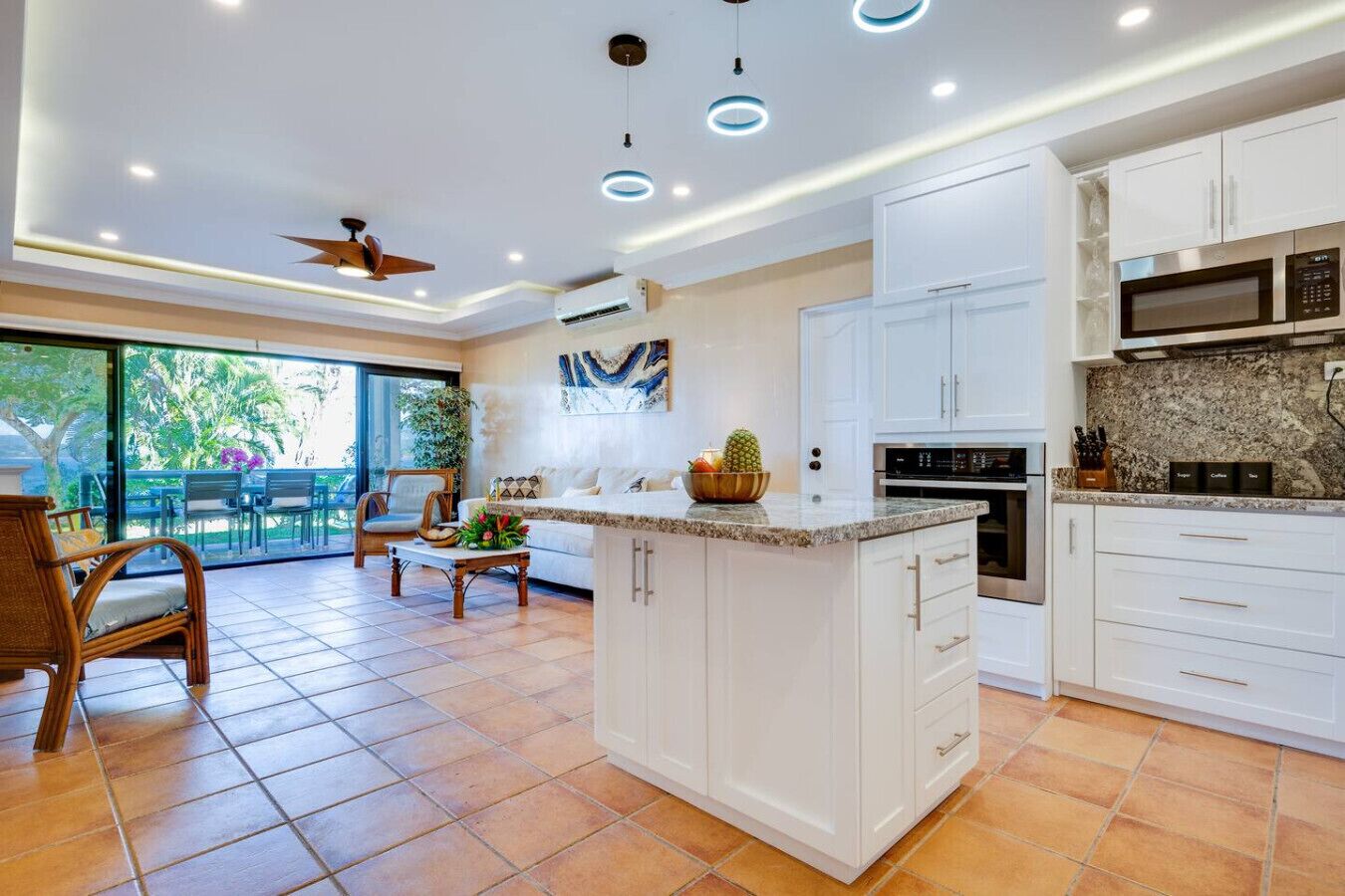 Una cocina moderna con armarios blancos, una isla grande y un comedor con vistas.