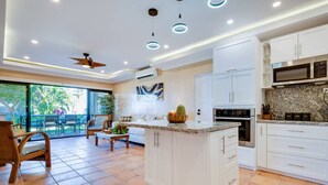 Una cocina moderna con armarios blancos, una isla grande y un comedor con vistas.