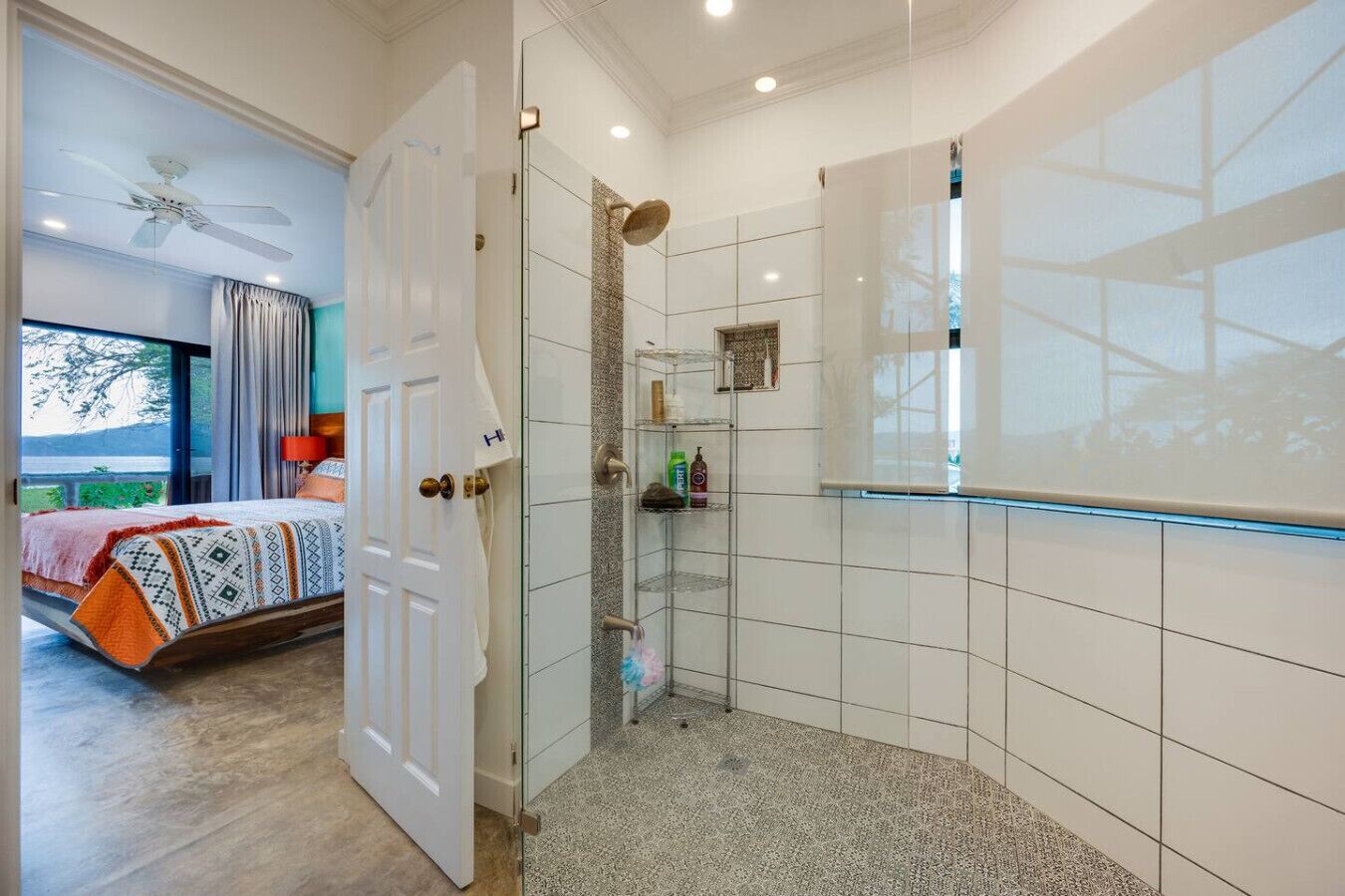 A hotel room with a bed, a shower area, and a view of the outdoors.