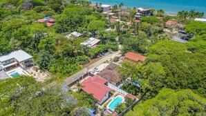 Ovenfra set udsigt over et kystnære boligområde med huse, en swimmingpool og havudsigt.