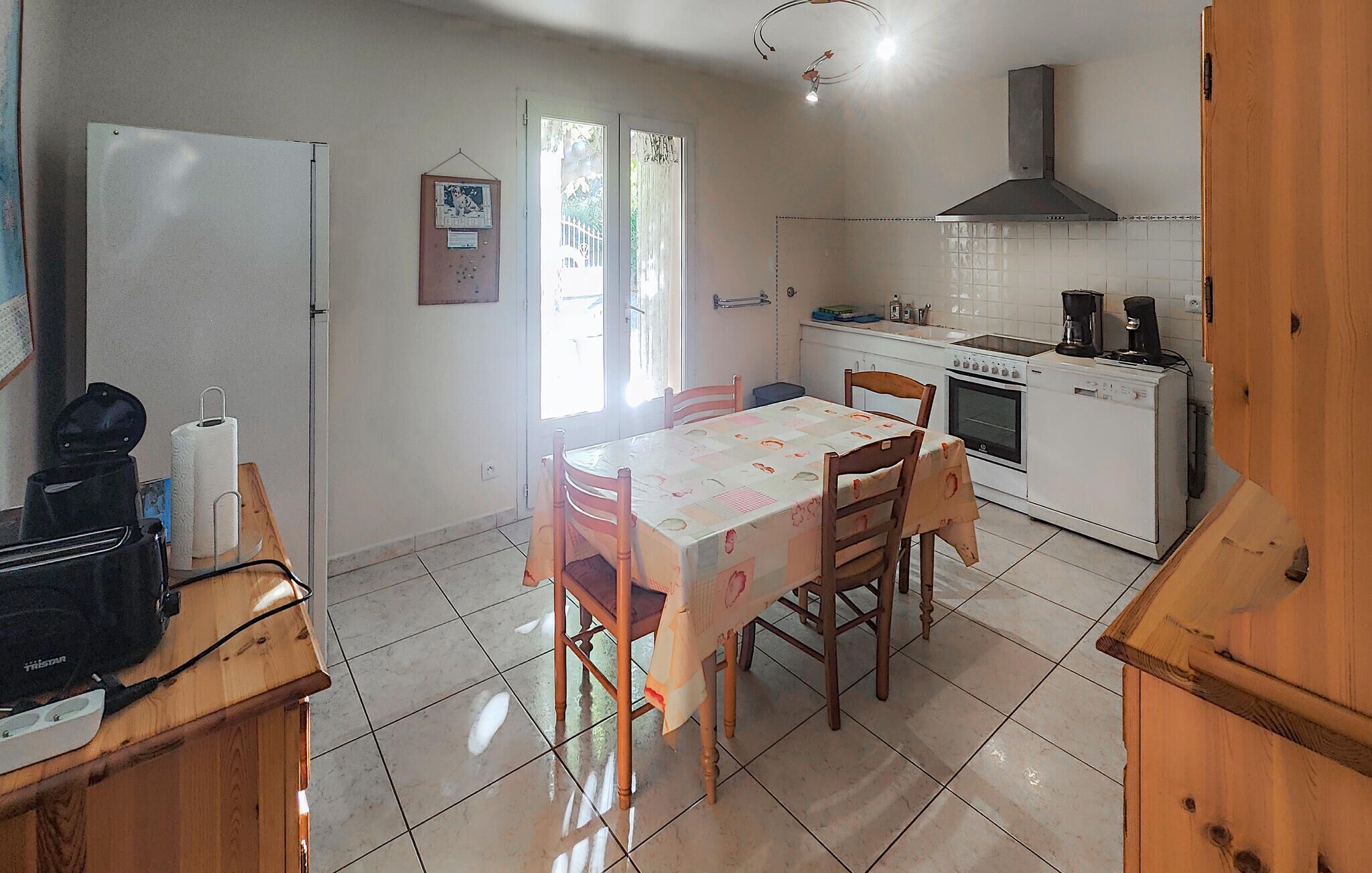 Uma cozinha compacta com mesa de jantar, cadeiras, geladeira, fogão e pia.