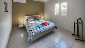 Una camera da letto con un letto, comodini, un lampadario e una finestra, con una scala in legno.