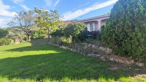 Una casa con un prato curato e diverse piante e arbusti.
