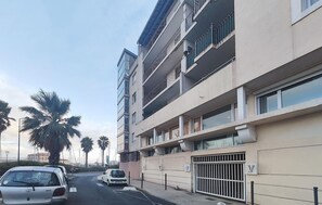 A multi-story residential building with balconies, a gated entrance, and palm trees in the background. - 2 bedroom pet friendly apartment in Sète (Sète)
