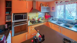 Keittiössä on oranssit kaapit, mikroaaltouuni, uuni ja pesuallas.