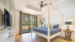 Quarto com cama de dossel, televisão e vista para o exterior.