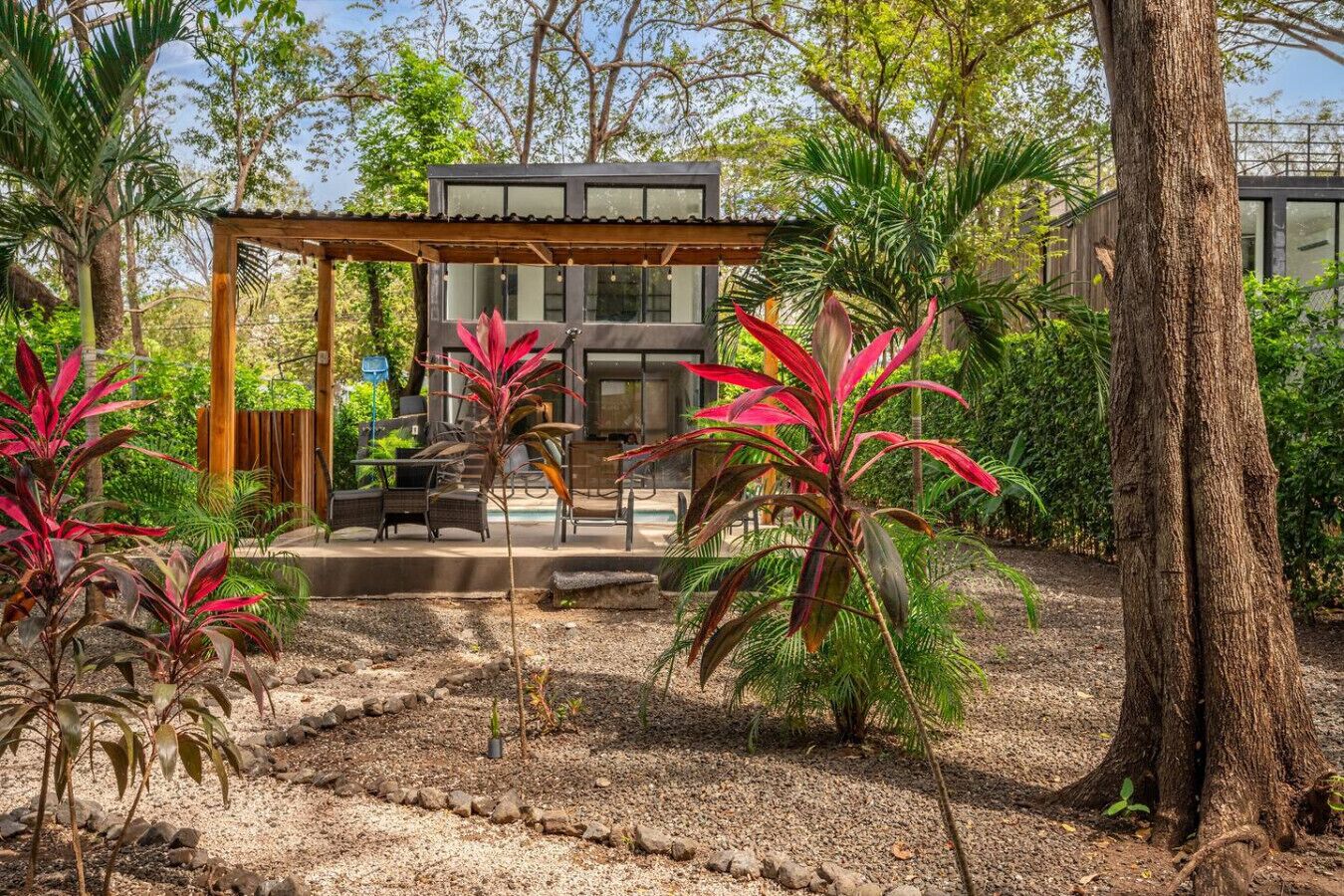 A modern outdoor patio with a pergola, seating area, and a pool.