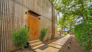 A modern building with a wooden exterior, a wooden door, and a concrete pathway leading to the entrance. - Casa Teca in Surfside w/ Pool near Beach (Potrero)