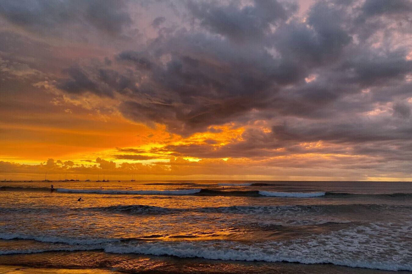 Une plage avec des vagues et un coucher de soleil.