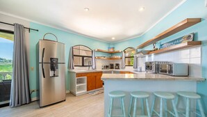 Eine moderne Küche mit Kühlschrank, Kaffeemaschine, Mikrowelle und Barhocker.