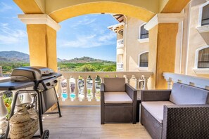 Eine Terrasse im Freien mit Korbmöbeln, einem Grill und Blick auf Pool und Berge.