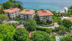 A resort with multiple buildings, a swimming pool, and a view of the sea. - Oceanfront Condo with Pool & Stunning Views (Playa Flamingo)