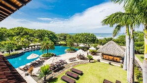 Een resort met een zwembad, loungegedeeltes en uitzicht op de oceaan.