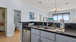 A modern kitchen with stainless steel appliances, a double sink, and a large window offering a view. - The View ~ Top Floor ~ Amazing Views (Dauphin Island)