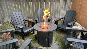 A circular fire pit with flames, surrounded by four Adirondack chairs. - 2 Homes Downtown Whitefish w/ Hot Tubs & Big Yard (Whitefish)