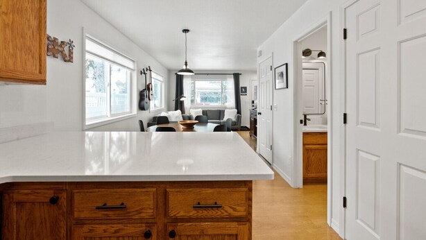 A modern kitchen with a central island, wooden cabinets, and a dining area with a sofa and chairs. - 2 Homes Downtown Whitefish w/ Hot Tubs & Big Yard (Whitefish)