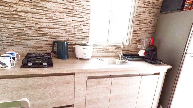 Una cocina de diseño moderno, con encimera de madera, estufa integrada, hervidor y cafetera.