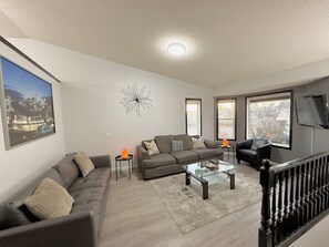 A modern living room with a sofa set, a glass coffee table, and a decorative wall piece. - 9 min airport|Great view|Game room|Sleep 10|Garage (Calgary)