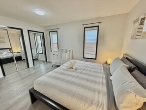 A bedroom with a large bed, a crib, and a mirror. - 9 min airport|Great view|Game room|Sleep 10|Garage (Calgary)