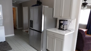 A compact kitchen with a stainless steel refrigerator, a coffee maker, and patterned flooring. - Moses Lake Mid-Century Gemstone: Cozy 2-bedroom house in the heart of town. (Moses Lake)