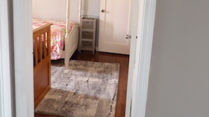 A bedroom with a wooden bed, a nightstand, a dresser, and a door with a coat rack. - Moses Lake Mid-Century Gemstone: Cozy 2-bedroom house in the heart of town. (Moses Lake)