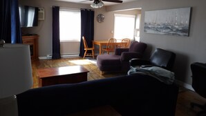 A living room with a ceiling fan, a dining table with chairs, a sofa, and a TV. - Moses Lake Mid-Century Gemstone: Cozy 2-bedroom house in the heart of town. (Moses Lake)
