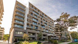 Un edificio residencial de varios pisos con balcones, fachada de ladrillo y un patio ajardinado.