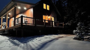 Eine Holzhütte mit verdeckter Veranda und einer verschneiten Einfahrt.