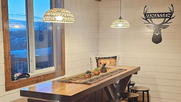 Eine Bar mit Holzboden, einer langen Theke, Hockern und Pendelleuchten.