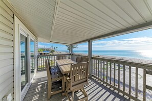 A wooden deck with a table and chairs overlooking a beach. - Beachside Retreat directly on the Gulf (Englewood)
