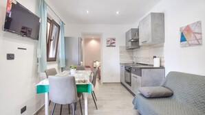 Een moderne keuken met een inbouwoven en een eethoek met een tafel en stoelen.