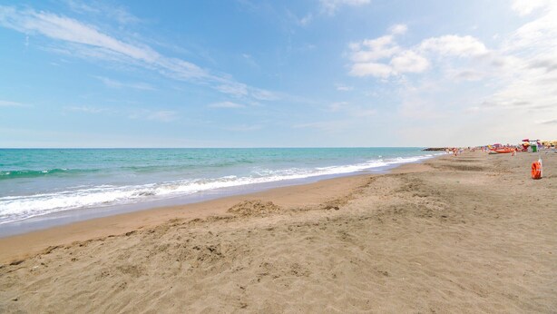 Een strand met heldere lucht en rustig water.