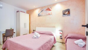 Een hotelkamer met twee bedden, een bureau, een stoel en een kledingkast.