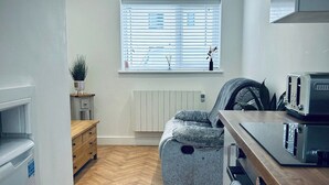 A compact kitchen with a herringbone wood floor, a built-in oven, and a window with blinds.