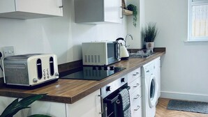 A compact kitchen with a microwave, toaster, and washing machine.