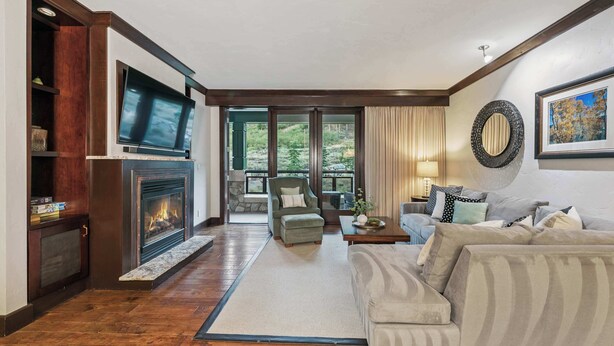 Un salón con chimenea, un sofá, un televisor y vistas al exterior.