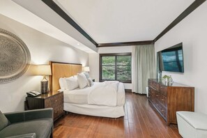 Ein Schlafzimmer mit Bett, Nachttisch, Schminktisch, Fernseher und einem Fenster mit Blick.