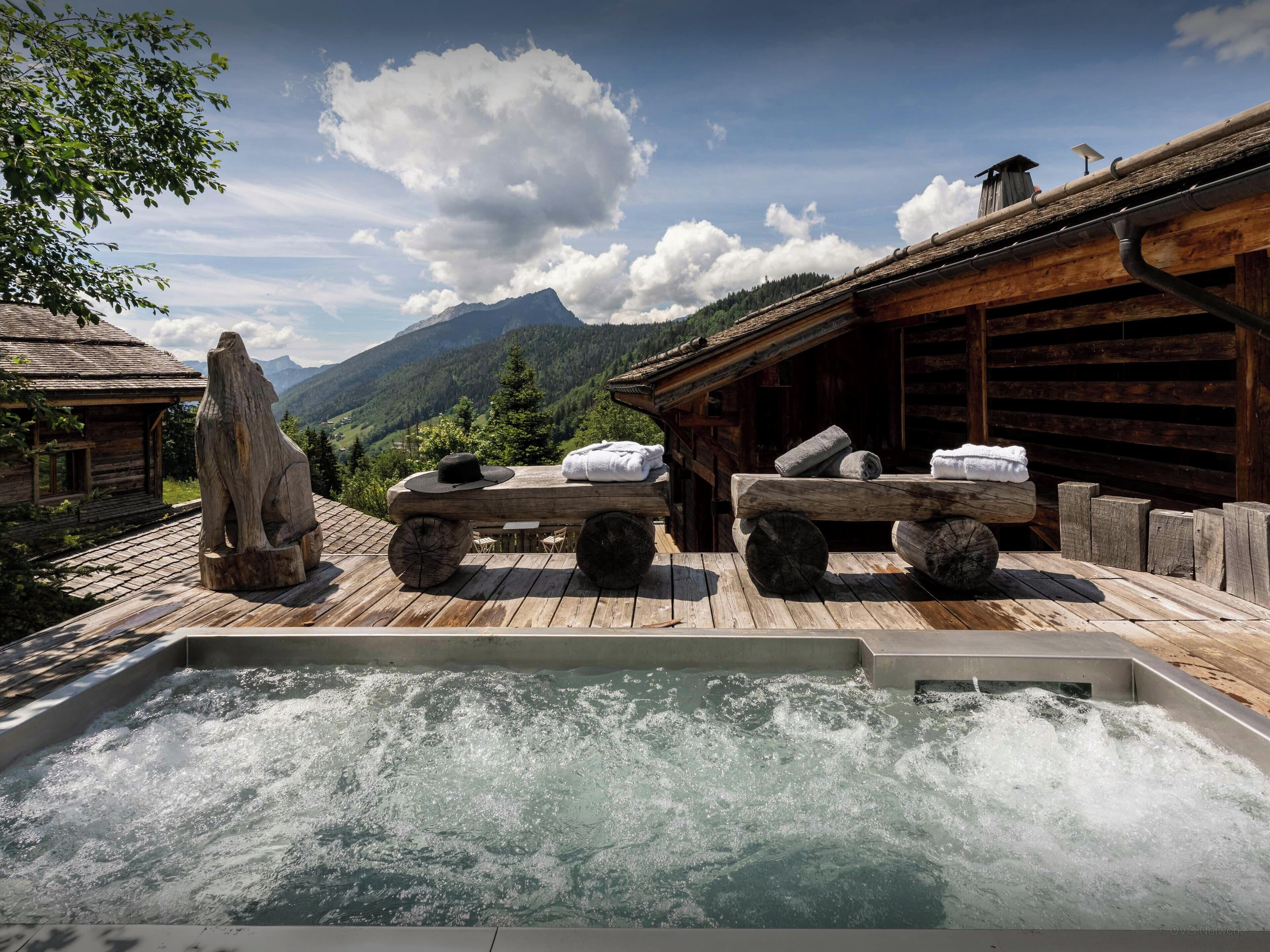 Eine Holzterrasse mit Whirlpool, Handtüchern und einem Hut.