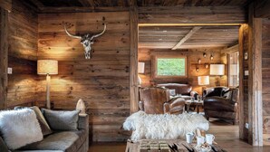 L’intérieur d’un chalet rustique, avec des murs en bois, un canapé en cuir, un tapis en fourrure et une table basse en bois.