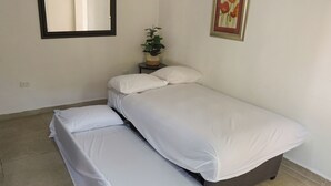 A neatly made bed with white linens in a room with a tiled floor, a small round table with a plant, and a framed picture on the wall. - Campestre La Fuente  (Monterrey)