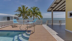 Uma área de piscina com espreguiçadeiras, piscina e vista para o oceano.