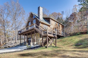 Une cabane en rondins avec des fondations en pierre, une terrasse en bois et une cheminée.