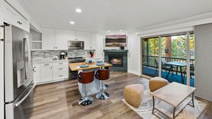 Una cocina moderna con armarios blancos, electrodomésticos de acero inoxidable y una isla central con taburetes de bar.