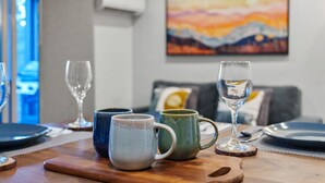 Una mesa de comedor con tazas de cerámica, una copa de vino y un plato listo para servir.
