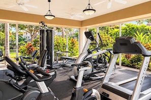 A gym with various exercise equipment, large windows, and a view of greenery outside. - Fairway Villas Waikoloa | 2 BR, Sleeps 6 | Car Incl. w/ 6+ Nights | FVW-L32 by KBM (Waikoloa Village)